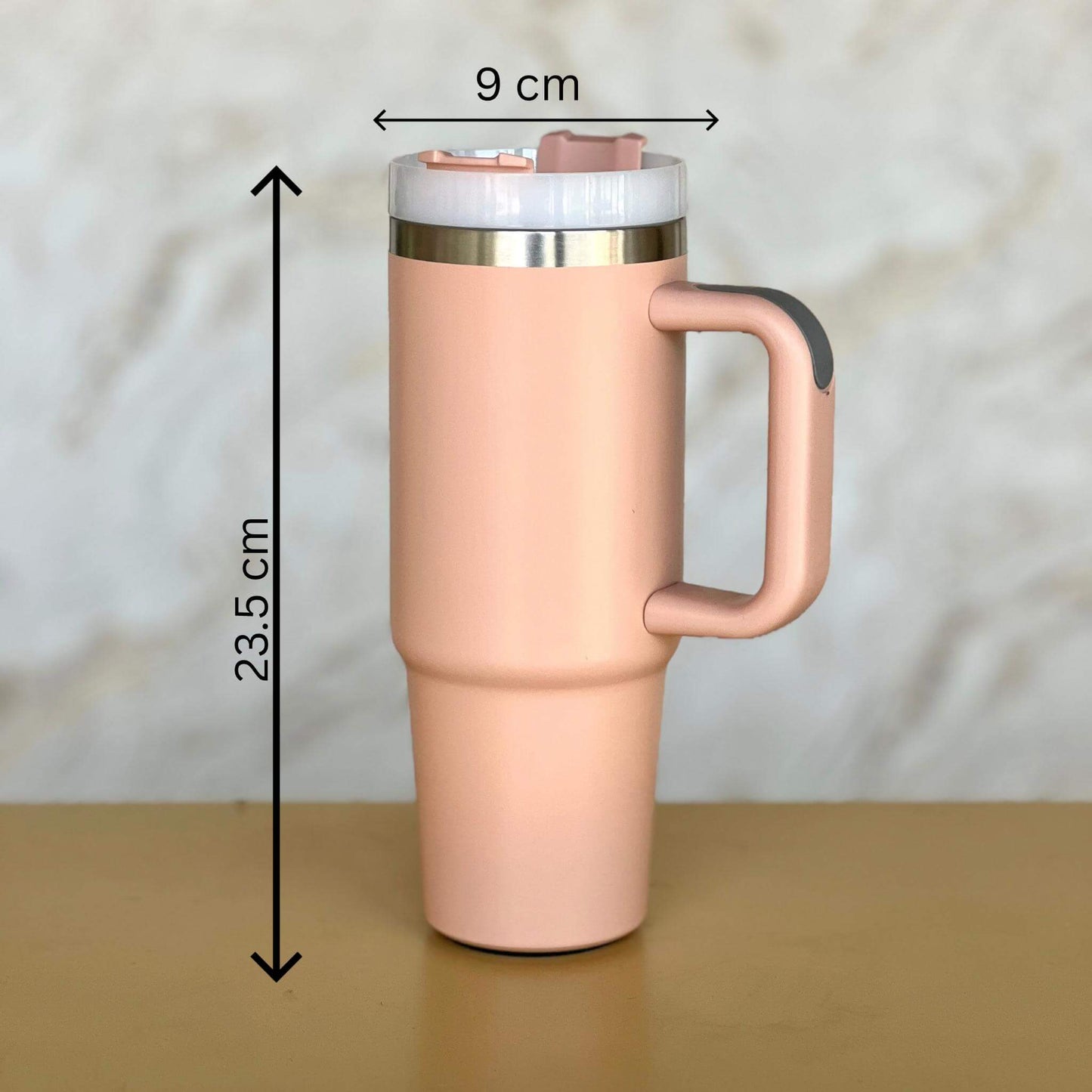 Peach travel mug with dimensions indicated on a beige background