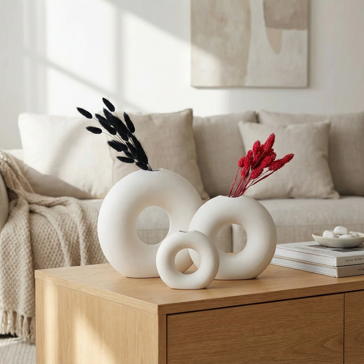 Ceramic flower vases with green foliage on a neutral background