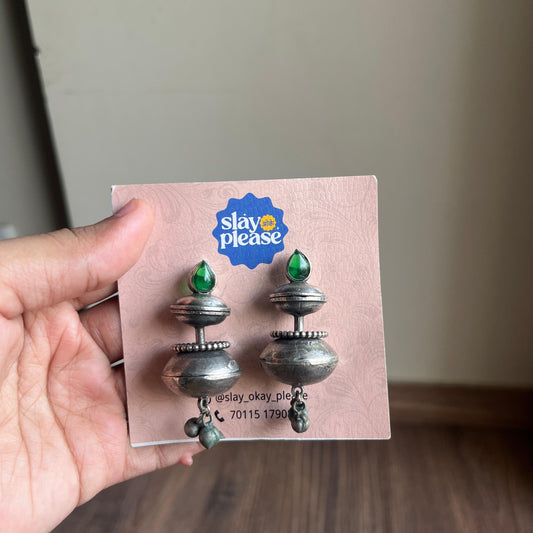 Earrings on a 'Slay Okay Please' branded card held by a hand.