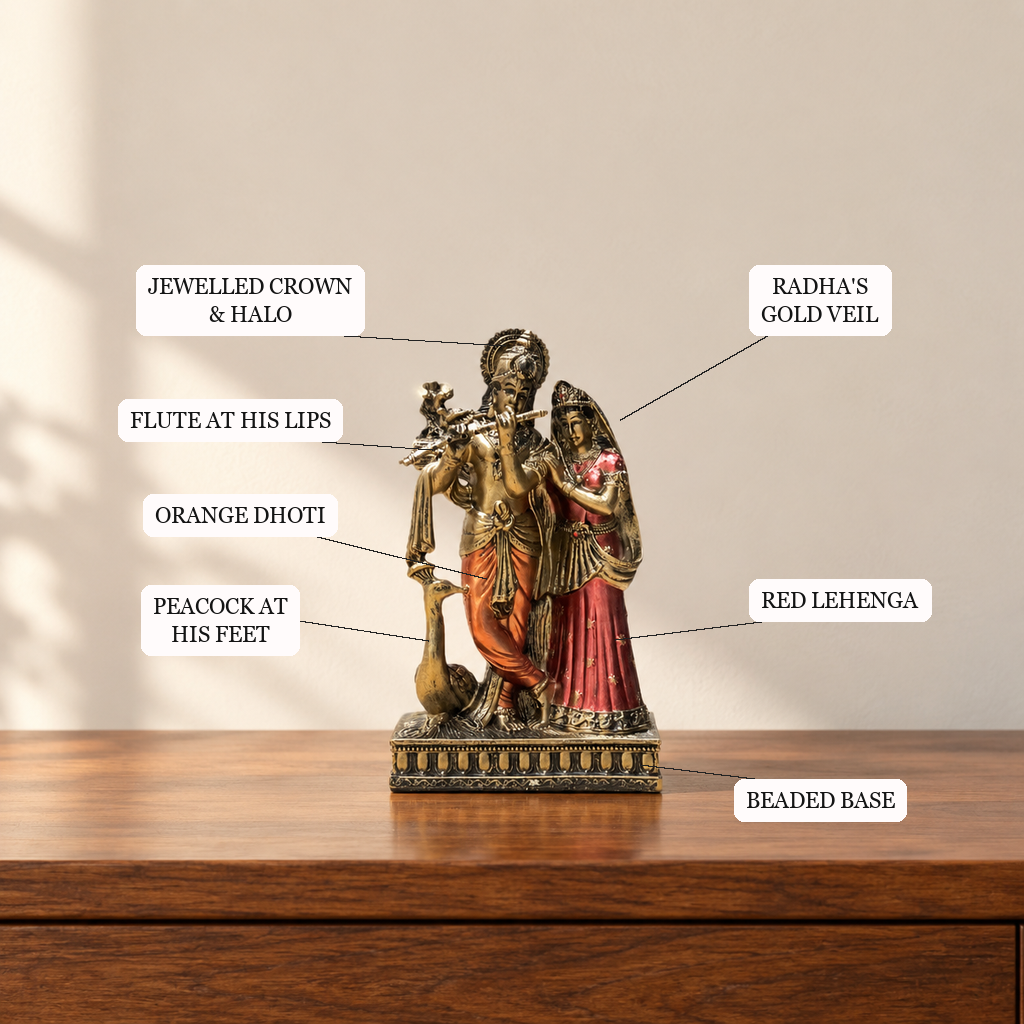 Radha Krishna idol features: crown and halo, flute, peacock, orange dhoti, Radha's gold veil, red lehenga, beaded base
