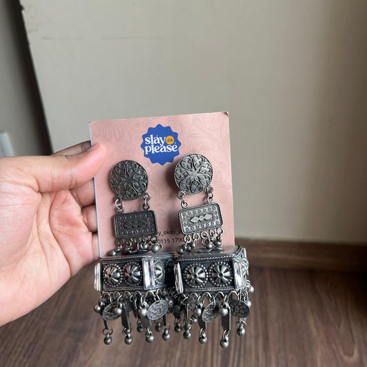 Silver earrings on a branded card held by a hand.