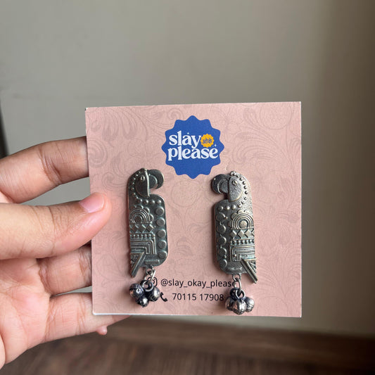 Metallic parrot-shaped earrings on a pink card.