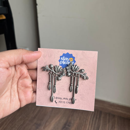 Silver brooch on a pink card held by a hand with a neutral background